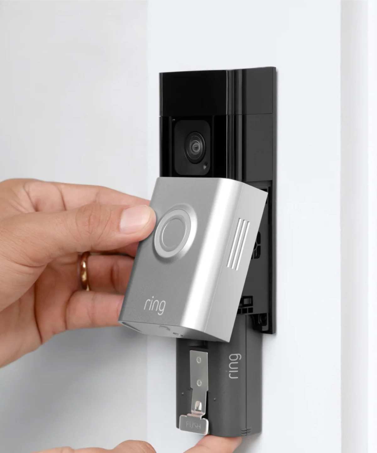 Two hands showing the battery release on a silver and black Ring Battery Doorbell Plus