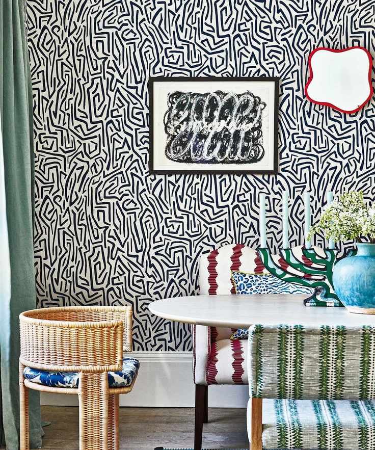 maximalist dining room with abstract, monochrome wallpaper, contrasting textured dining chairs