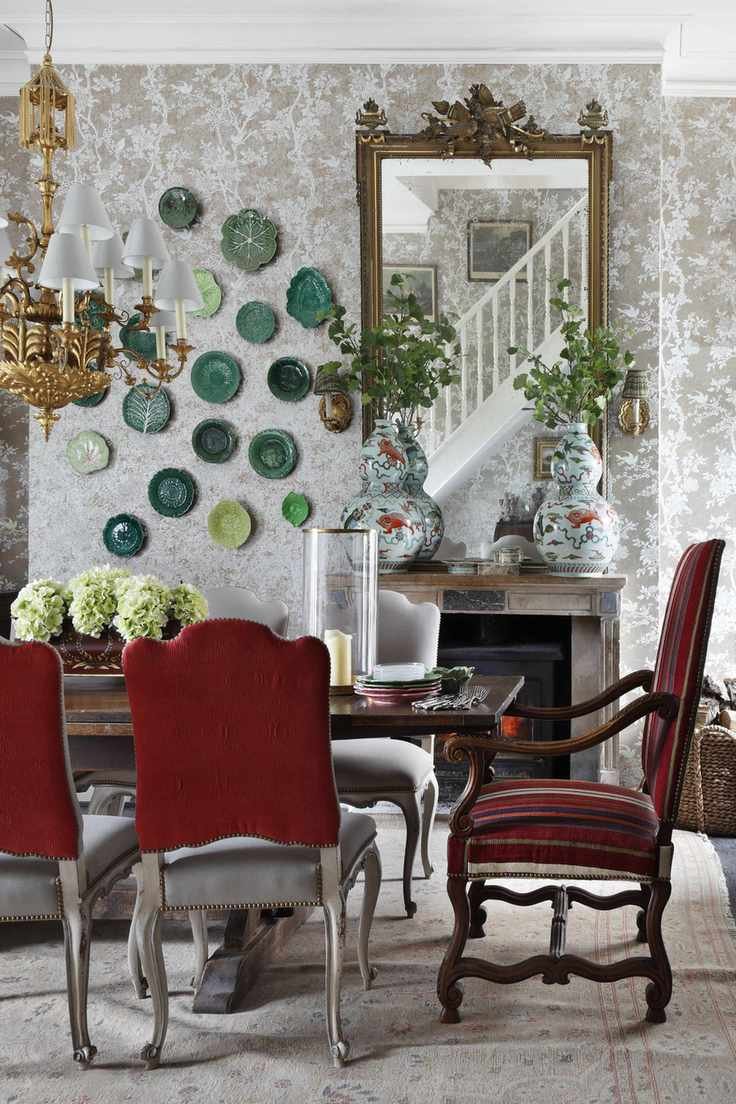 damask style wallaper in dining room with table setting, ornate mirror, plates on the wall, gold chandelier, upholstered dining chairs