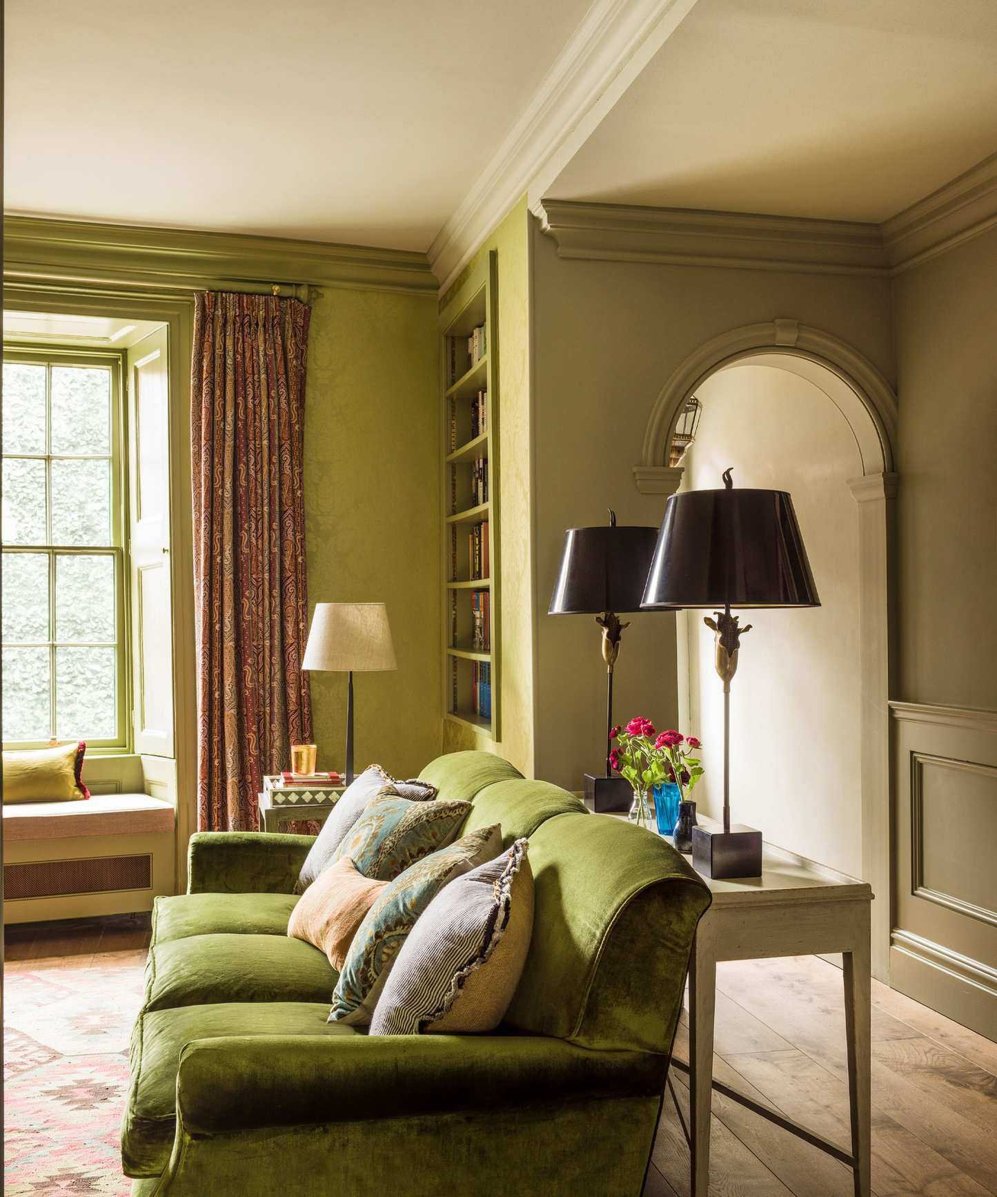 Traditional living room corner with green sofa and damask wallpaper, painted gray and white walls.